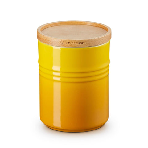 Yellow ceramic jar with wooden lid on a white background, featuring Le Creuset branding.